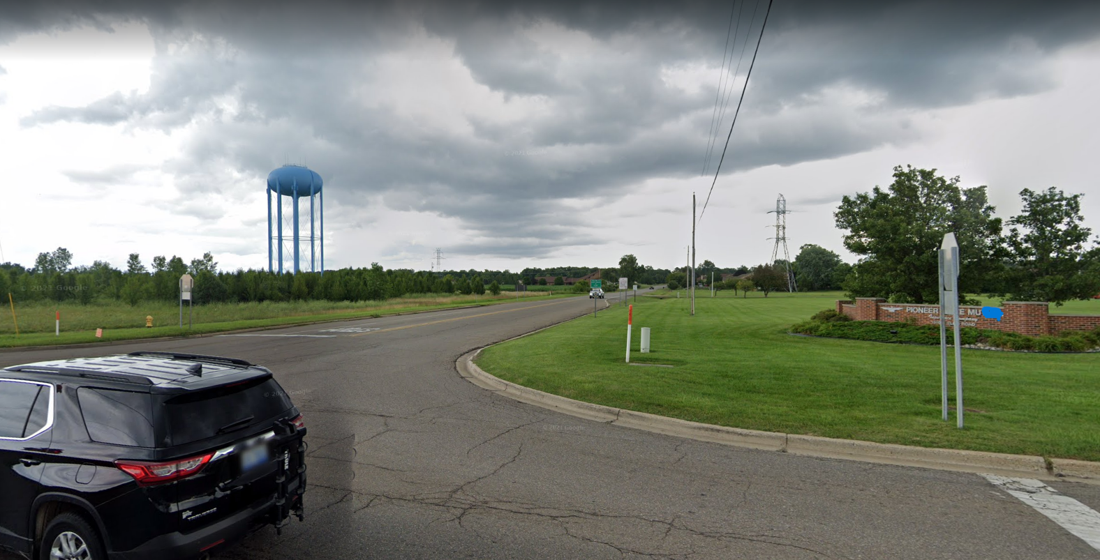 A screenshot of Google Street View, with a view of road, a water tower, and a sign of Pioneer [redacted]e mu[redacted].